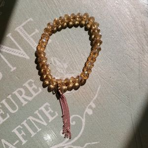 Bracelet with amber colored beads and pink tassels